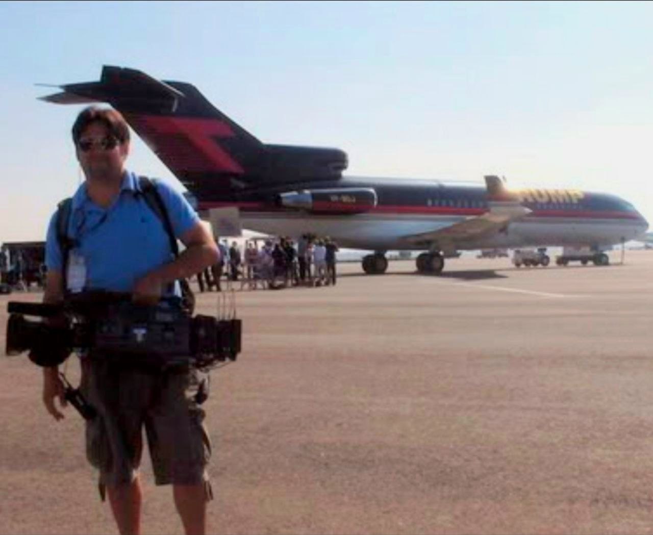 John Treviño operating a broadcast camera near an airplane